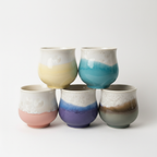Five ceramic cups with gradient colors on a white background