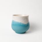 Ceramic cup with white top and blue gradient base on a white background