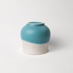 Ceramic cup with two-tone, white top, teal and light blue bottom design on a white background