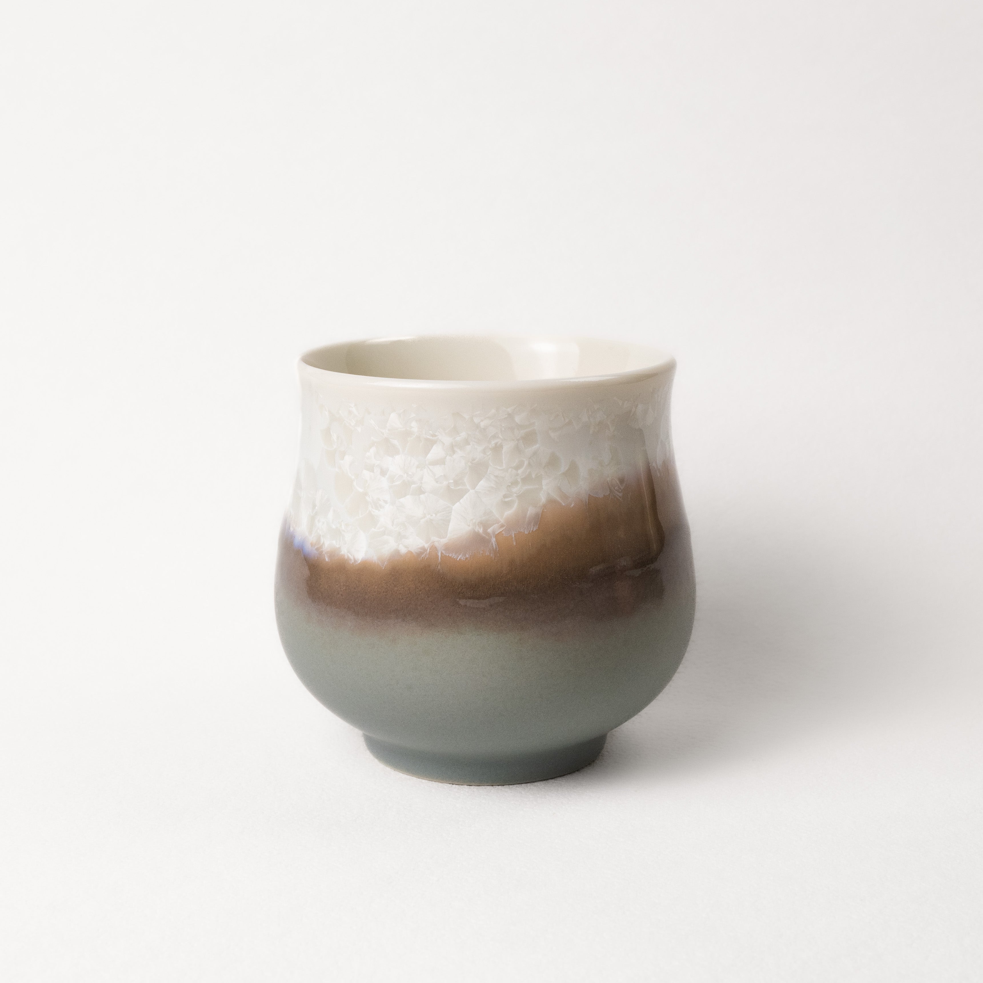 Ceramic cup with gradient grey, brown, and white crystalline color on a white background