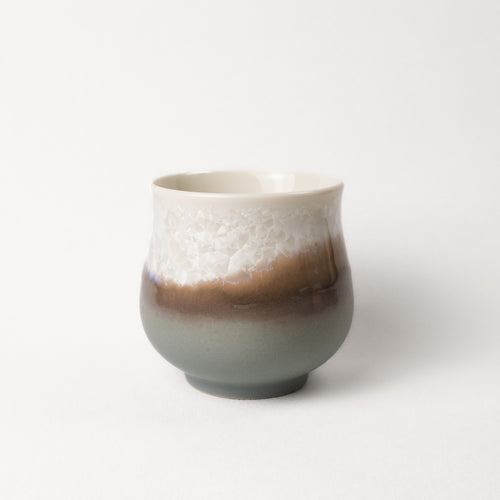 Ceramic cup with gradient grey, brown, and white crystalline color on a white background