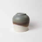 Ceramic tea cup with two-tone, grey, brown, and white design on a white background