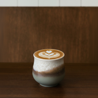 Cappuccino with latte art in a ceramic cup on a wooden surface.