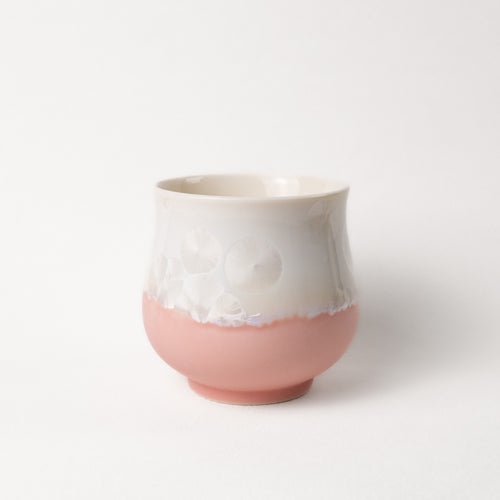 Ceramic cup with white top and pink bottom on a light gray background