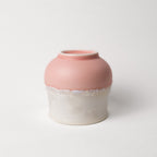 Ceramic cup with pink top and white bottom on a light gray background