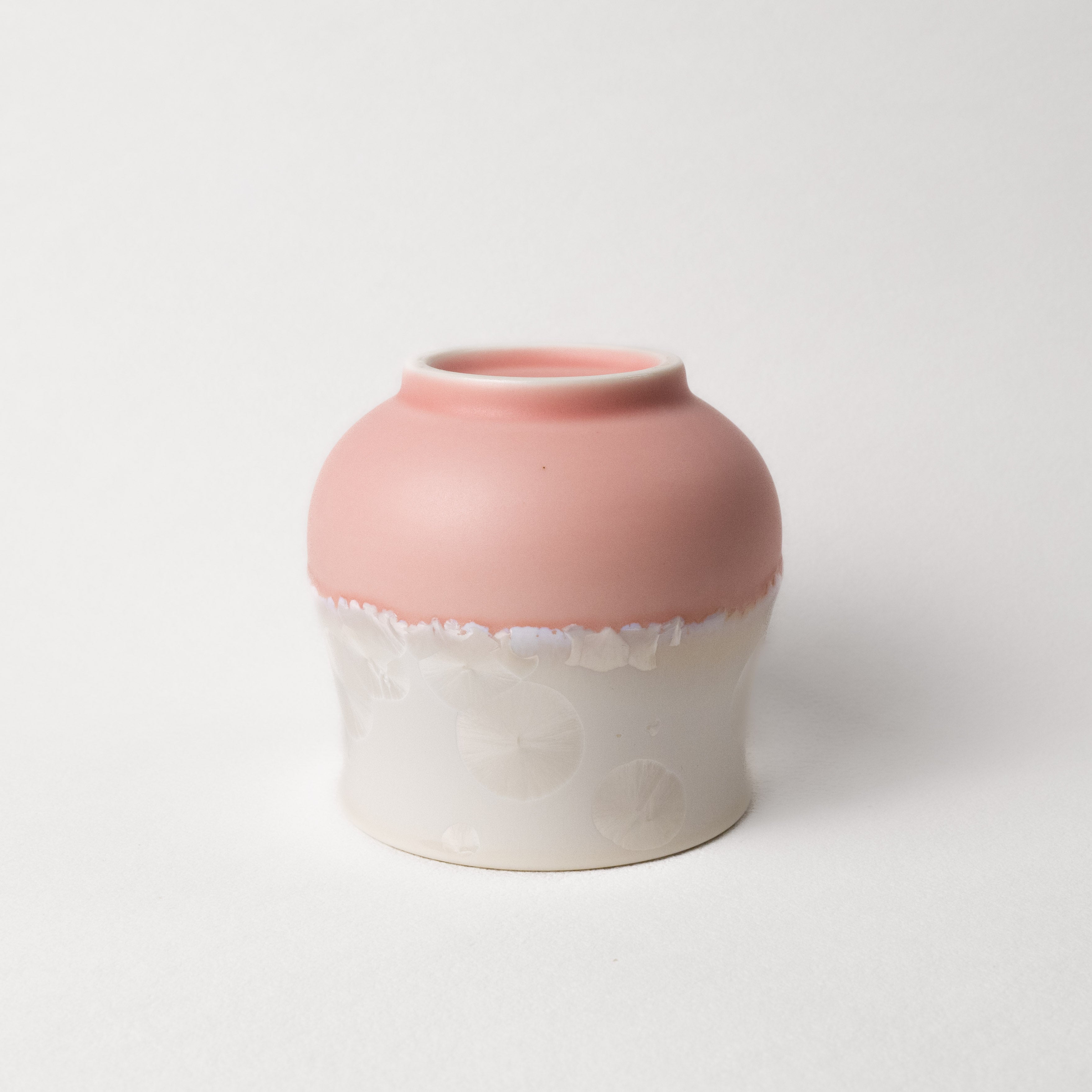 Ceramic cup with pink top and white bottom on a light gray background