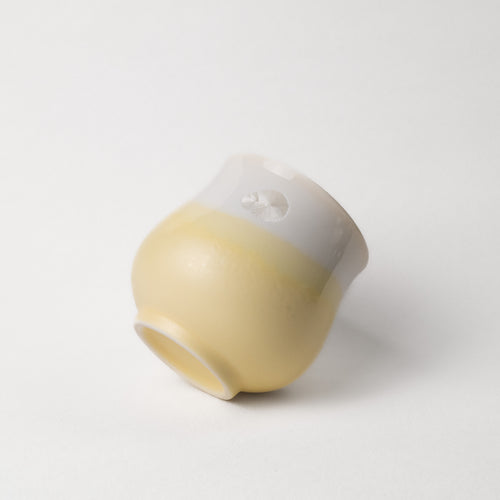 White and beige yellow ceramic cup on a light gray background