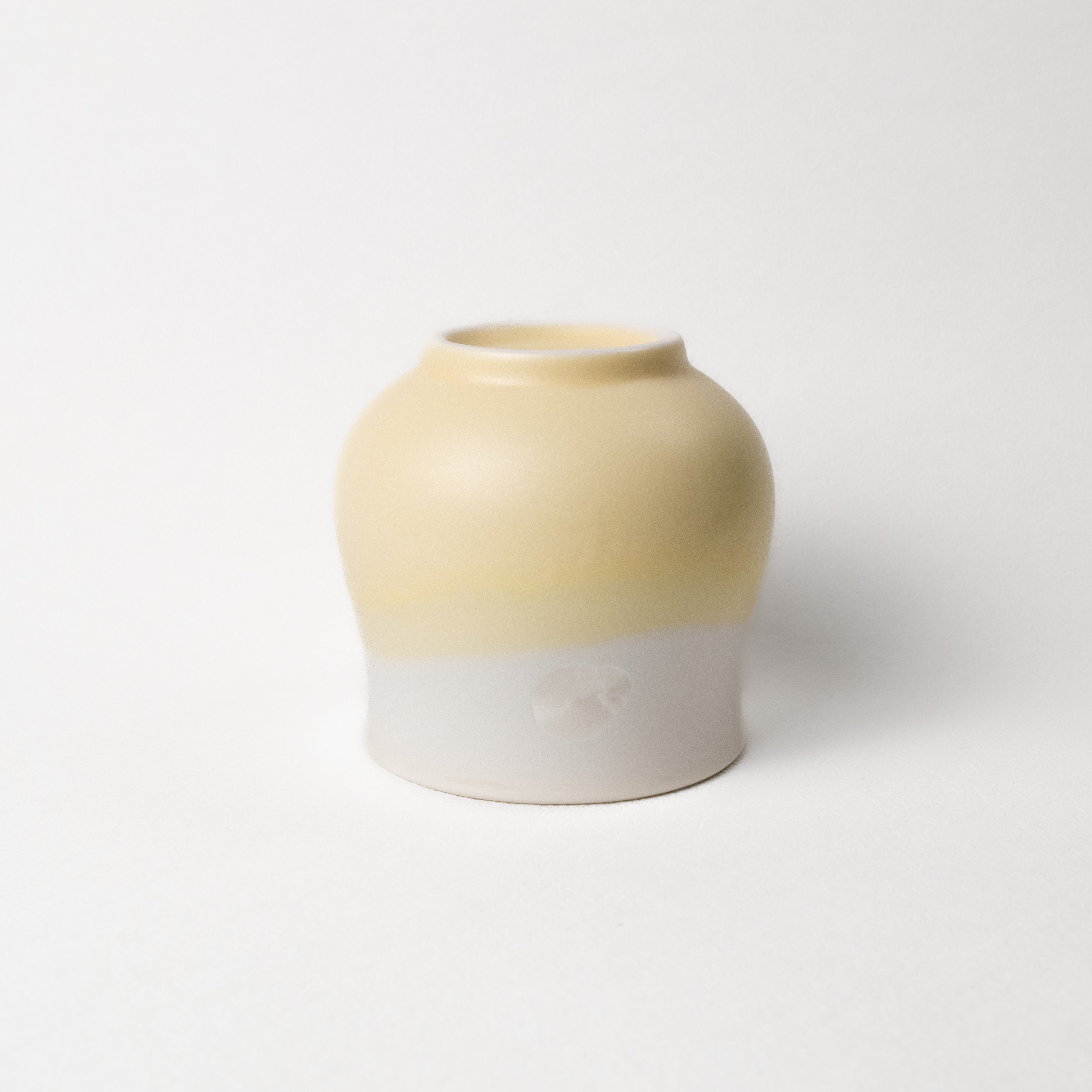 Ceramic vase with two-tone, white and yellow design on a white background