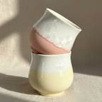 two ceramic cups stacked on a textured surface with a neutral background