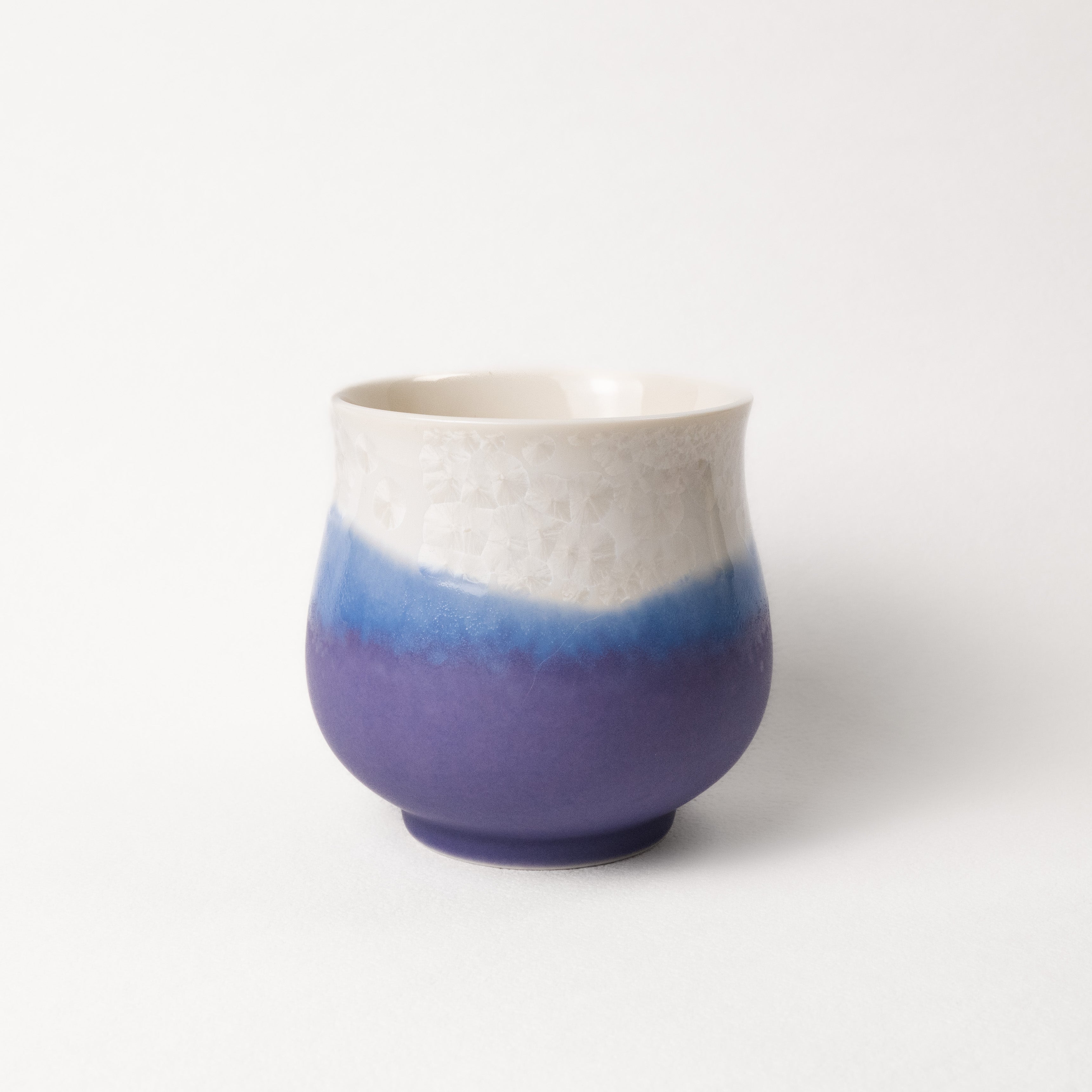 Ceramic cup with two-tone, white top, purple bottom design on a white background