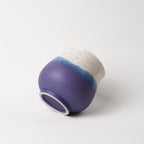 Ceramic cup with purple and white design on a light gray background