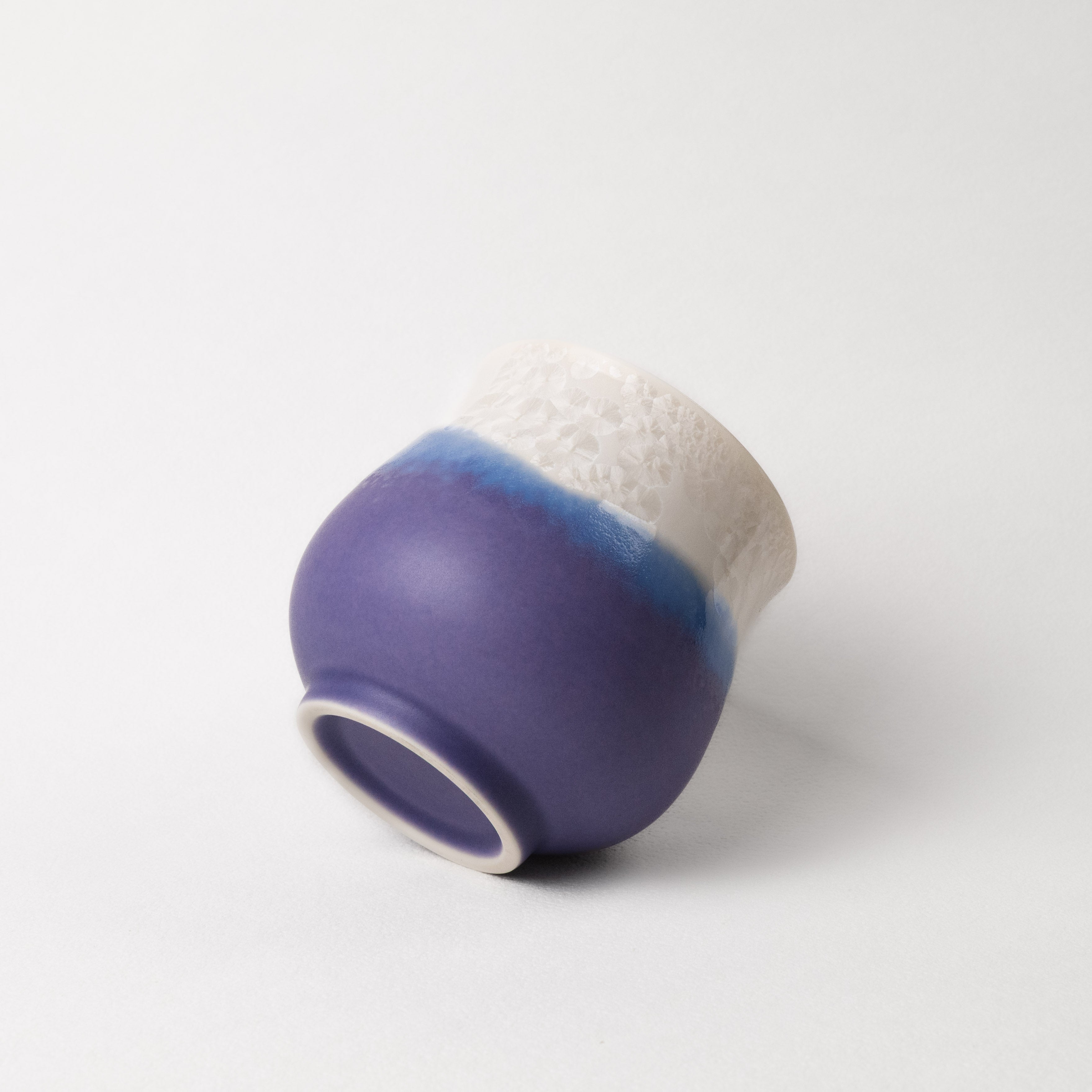 Ceramic cup with purple and white design on a light gray background