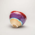 Colorful ceramic tea cup with a gradient from red to purple on a light gray background