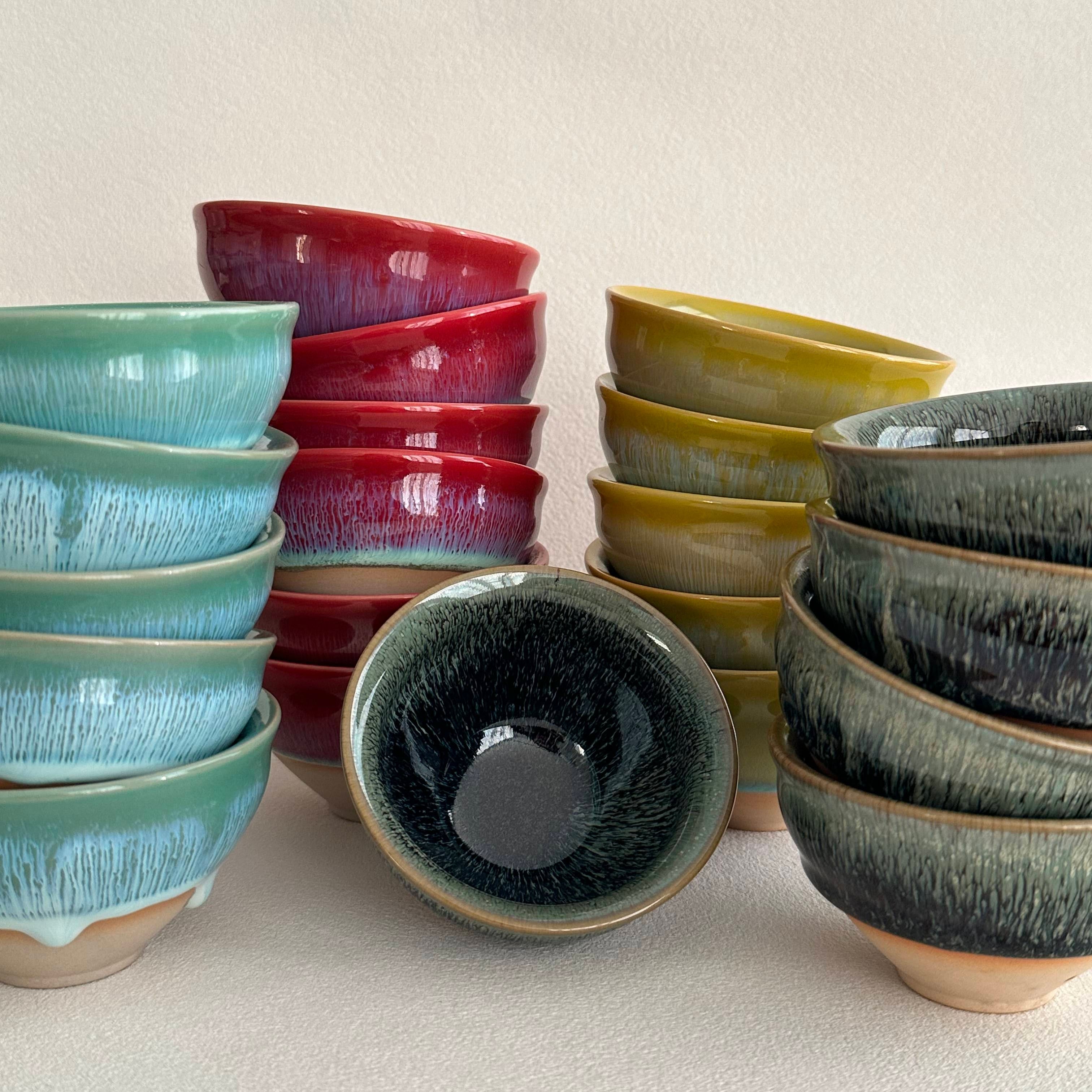 Set of ceramic bowls in various colors on a beige background