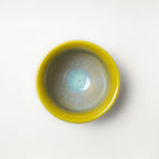 Yellow ceramic tea cup with a textured surface on a white background