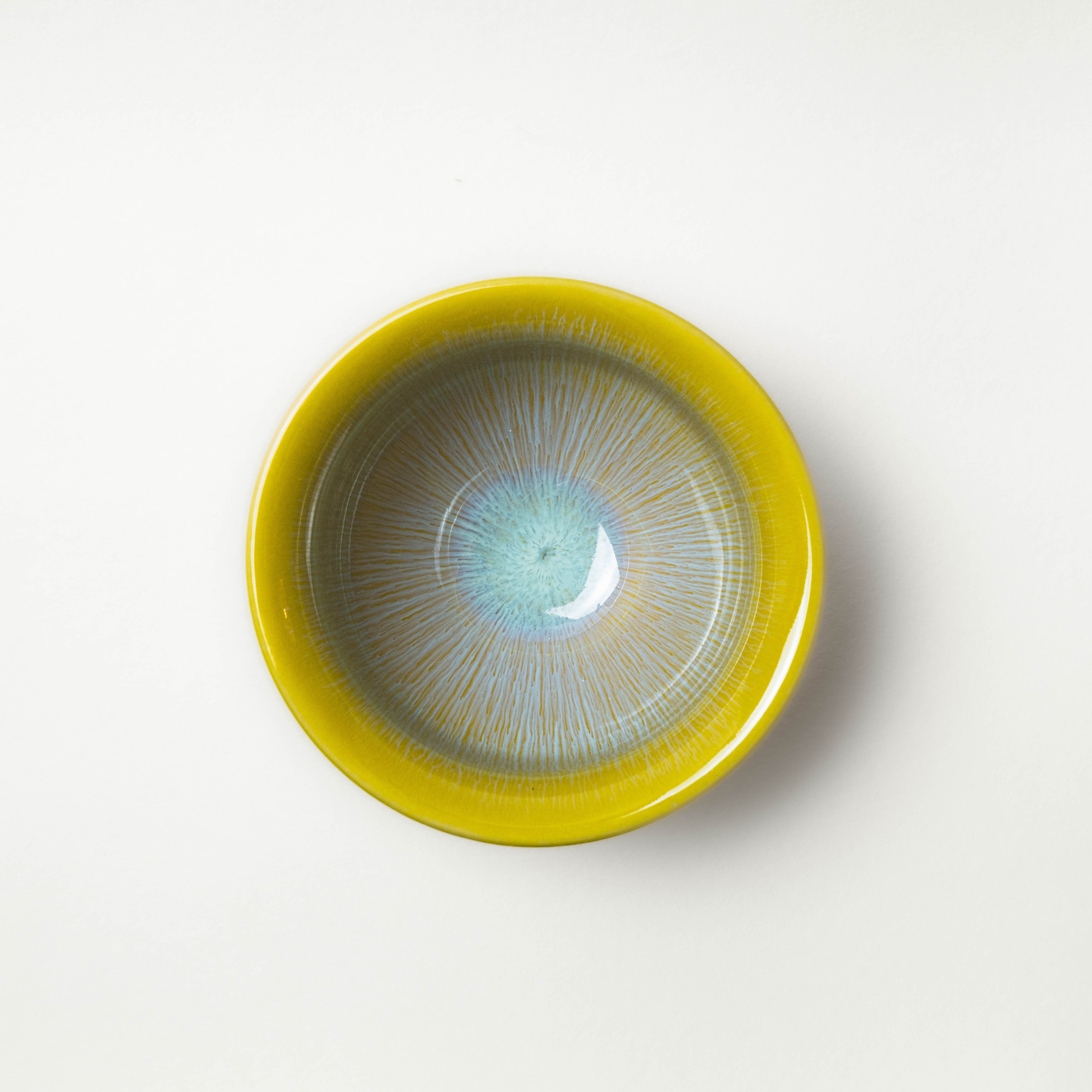 Yellow ceramic tea cup with a textured surface on a white background