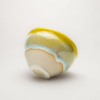 Ceramic tea cup with a yellow rim on a white background
