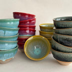 Set of ceramic bowls in various colors on a beige surface