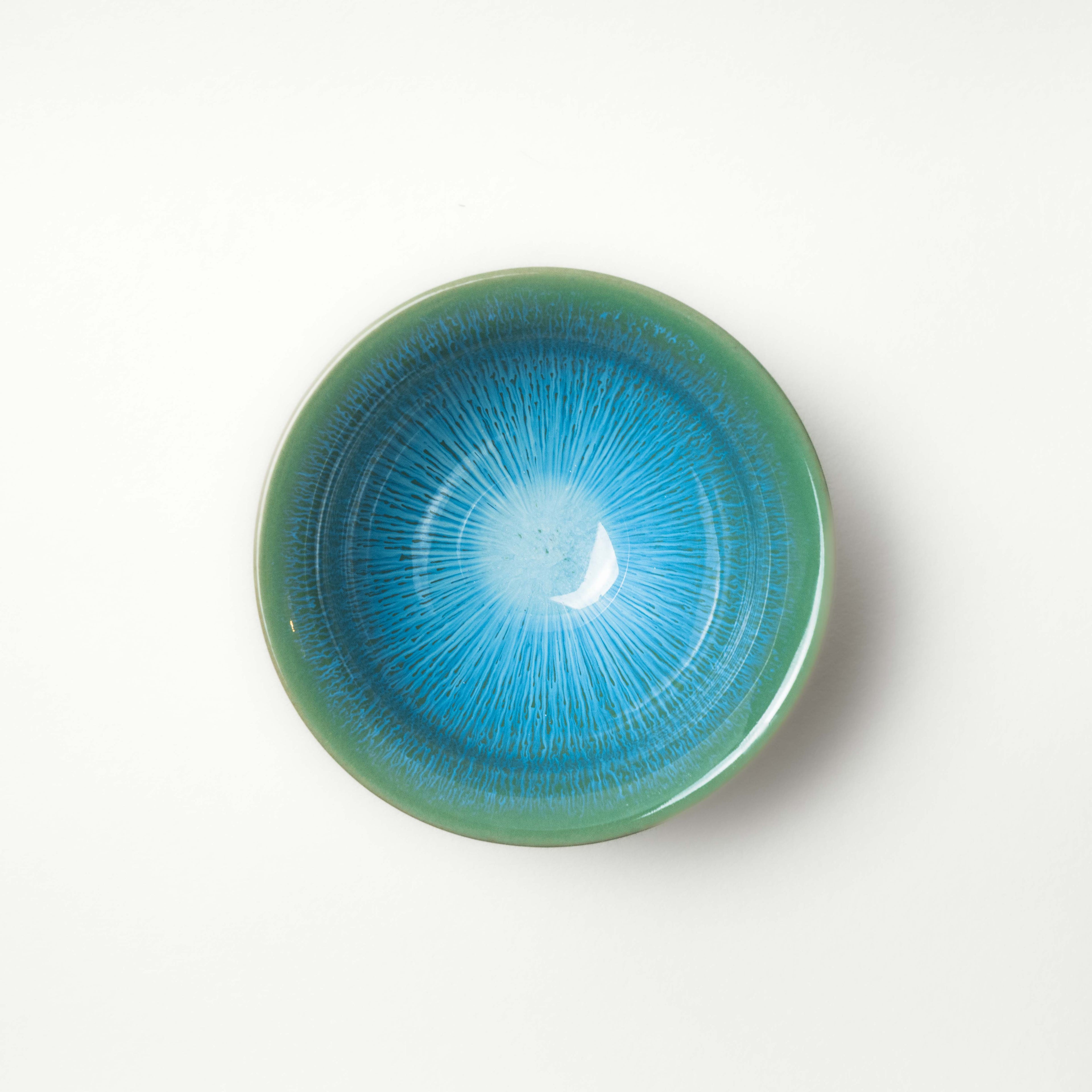 Ceramic tea cup with blue and green gradient glaze on a white background