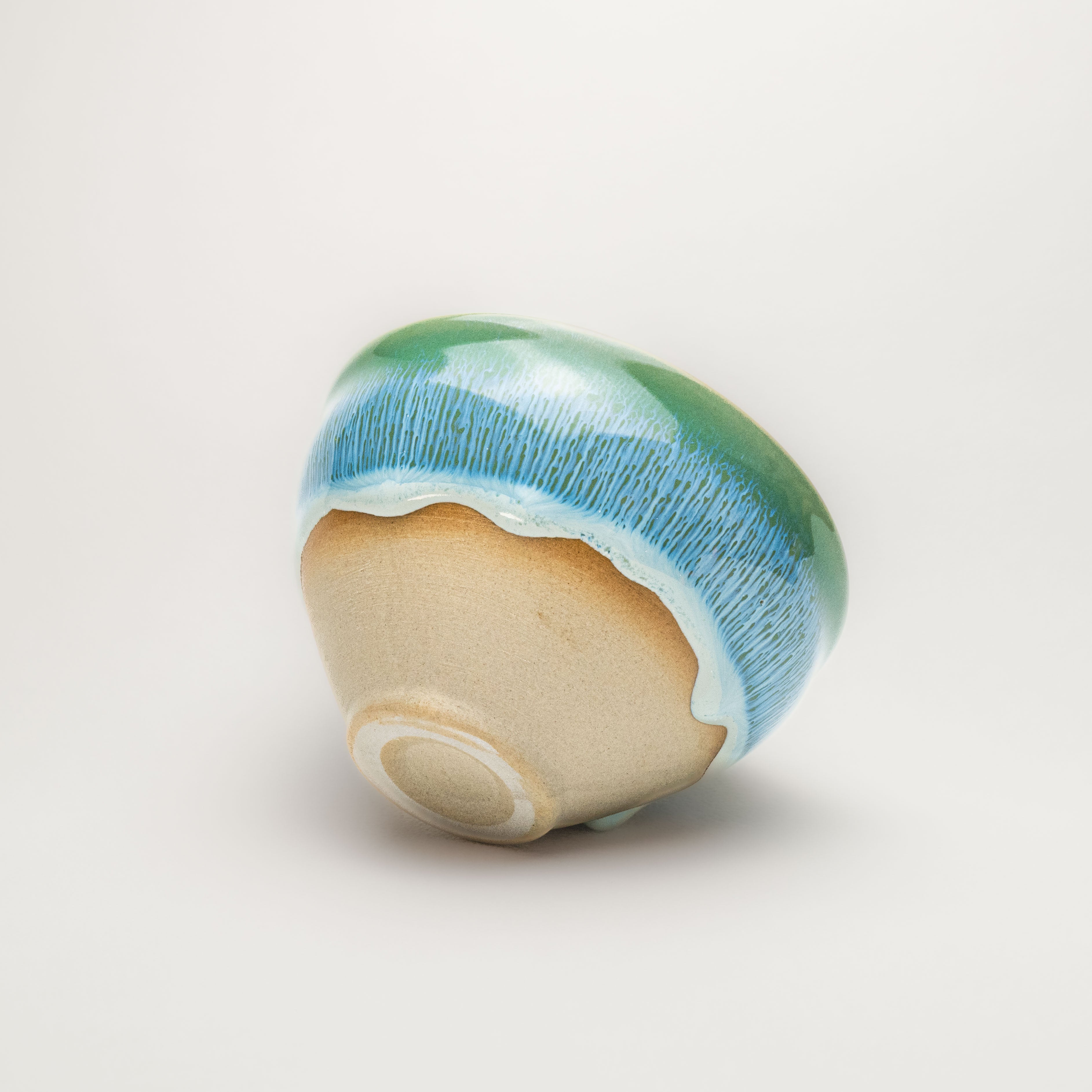 Ceramic tea cup with blue and beige glaze on a white background