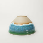 Ceramic tea cup with a textured blue and green rim on a white background