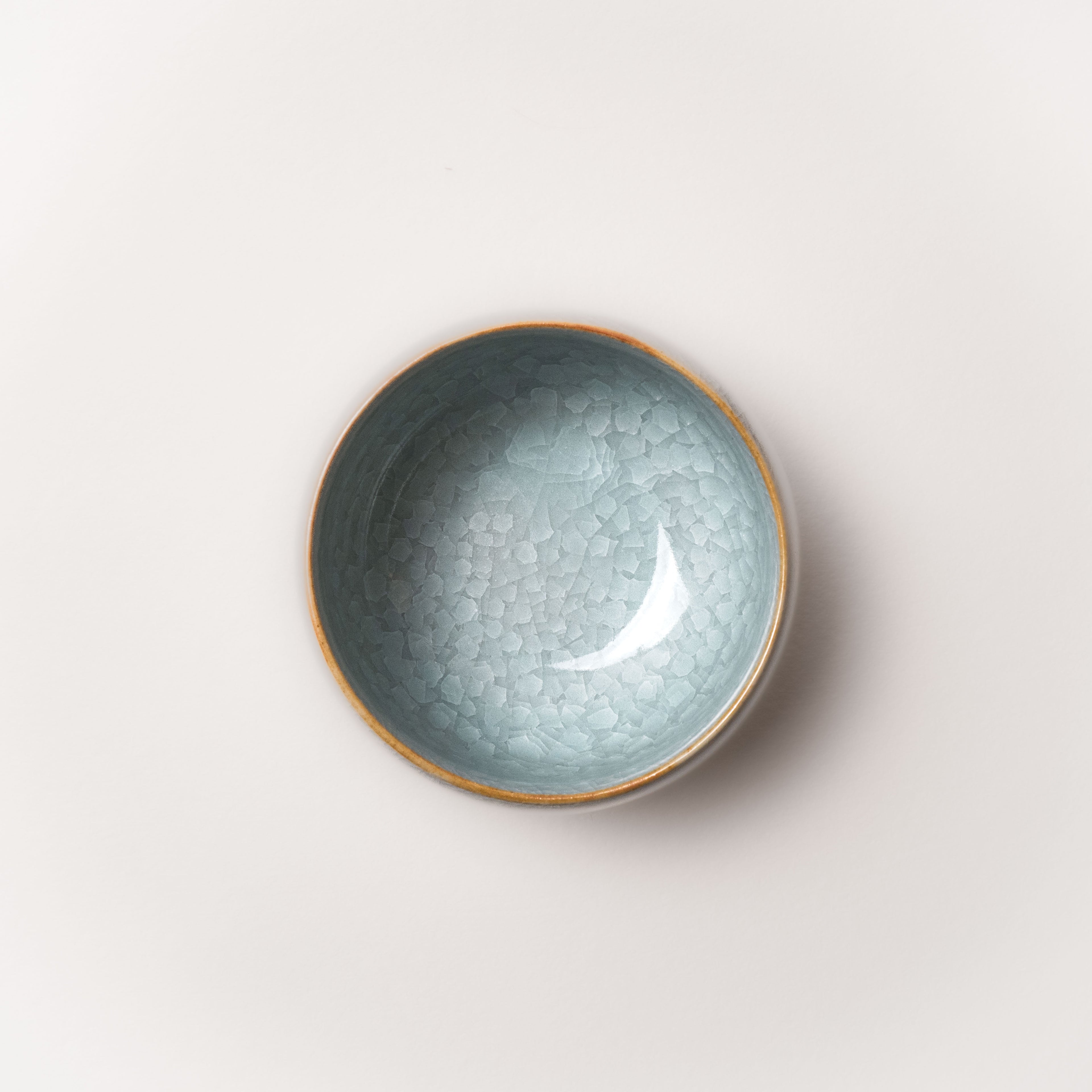 Ceramic tea cup with textured crackle glaze surface on a light gray background