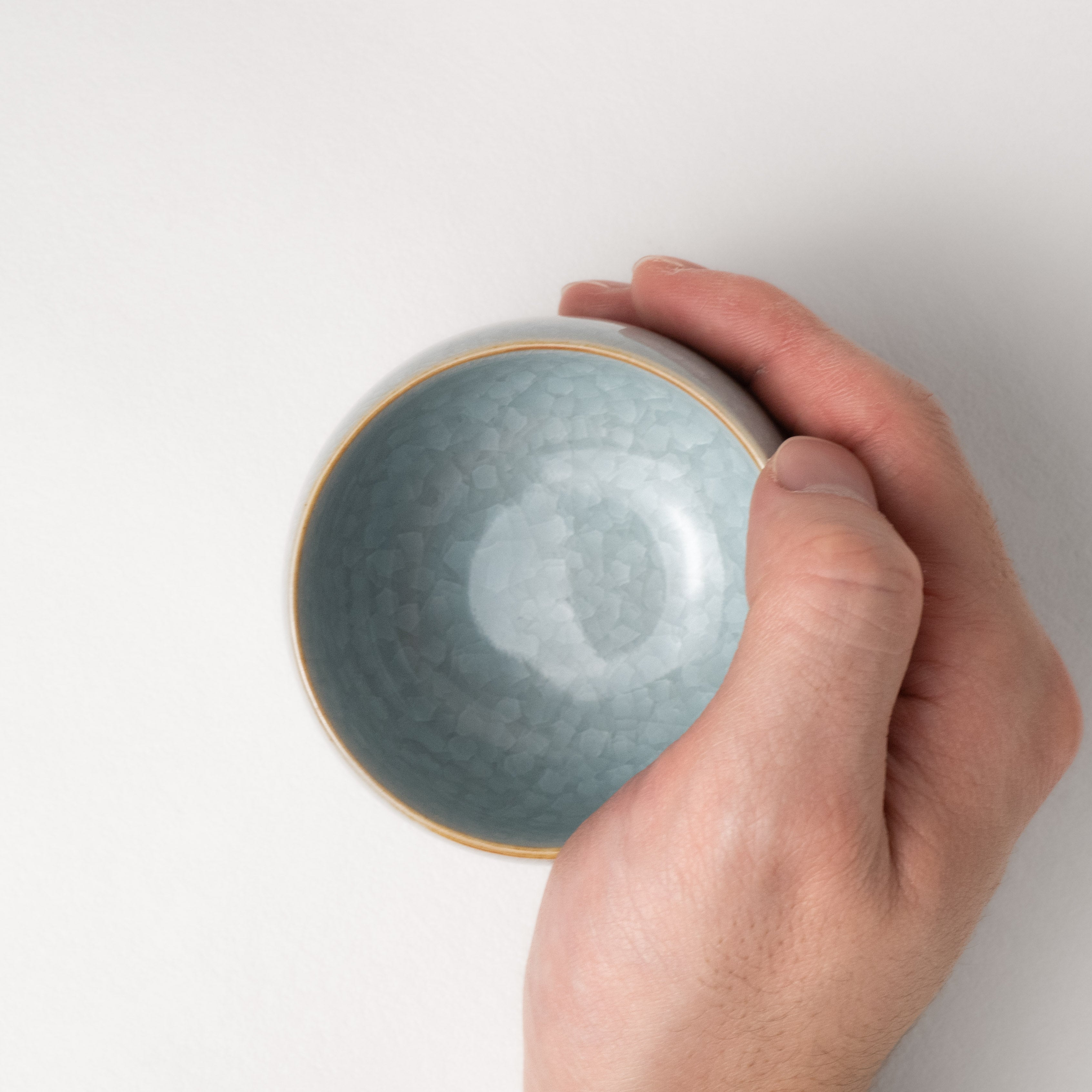 Hand holding a textured ceramic tea cup against a plain background