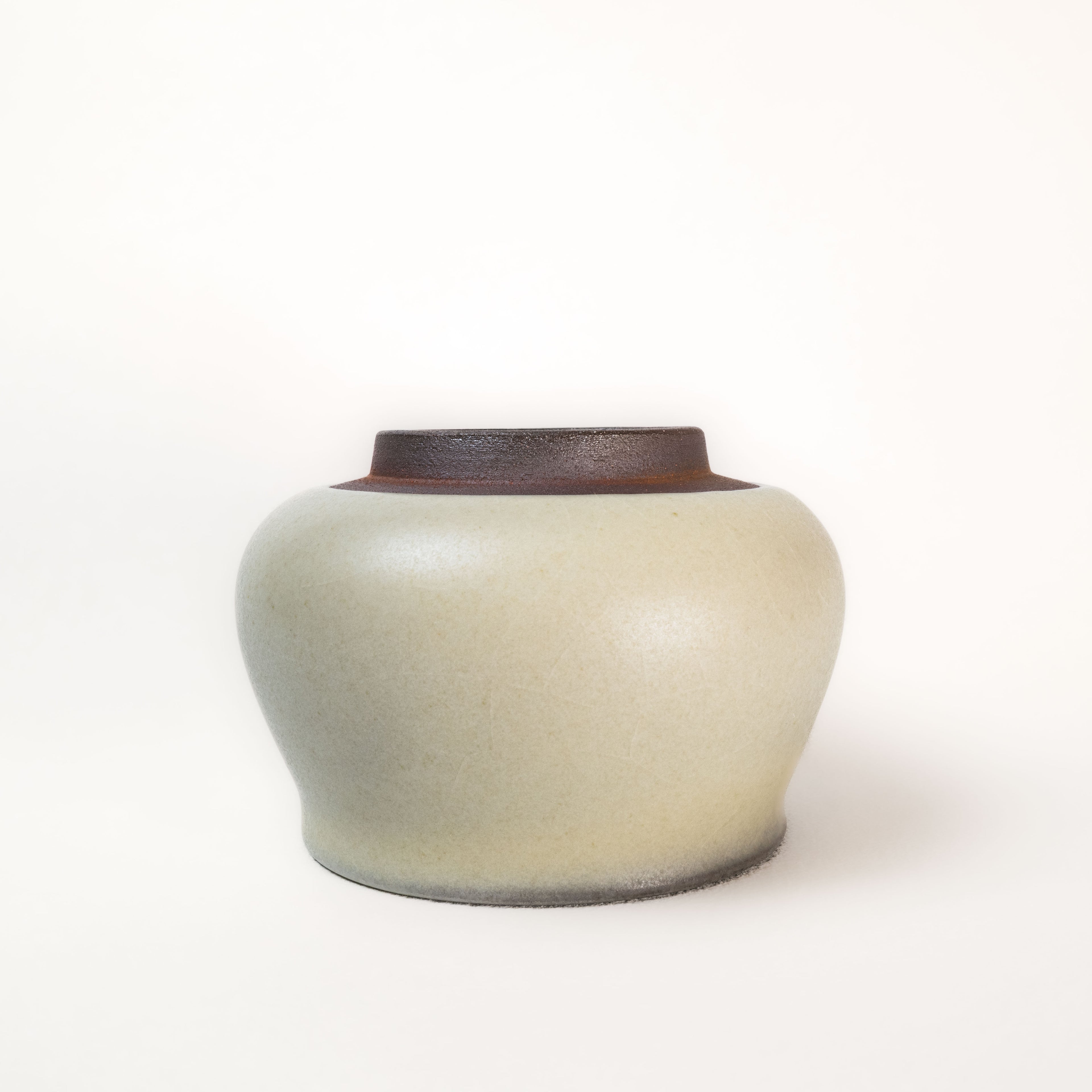 Ceramic cup with a brown top and beige body on a white background
